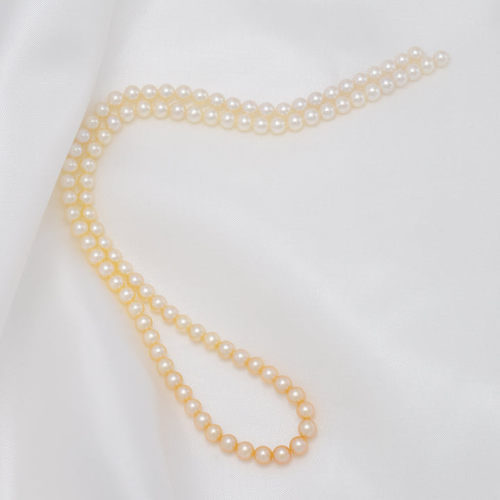 TF-22: 4-4.5 mm Natural-color Round Akoya Ombré Pearl Strand elegantly displayed on smooth white fabric, showcasing lustrous cultured akoya pearls in a subtle ombré effect.