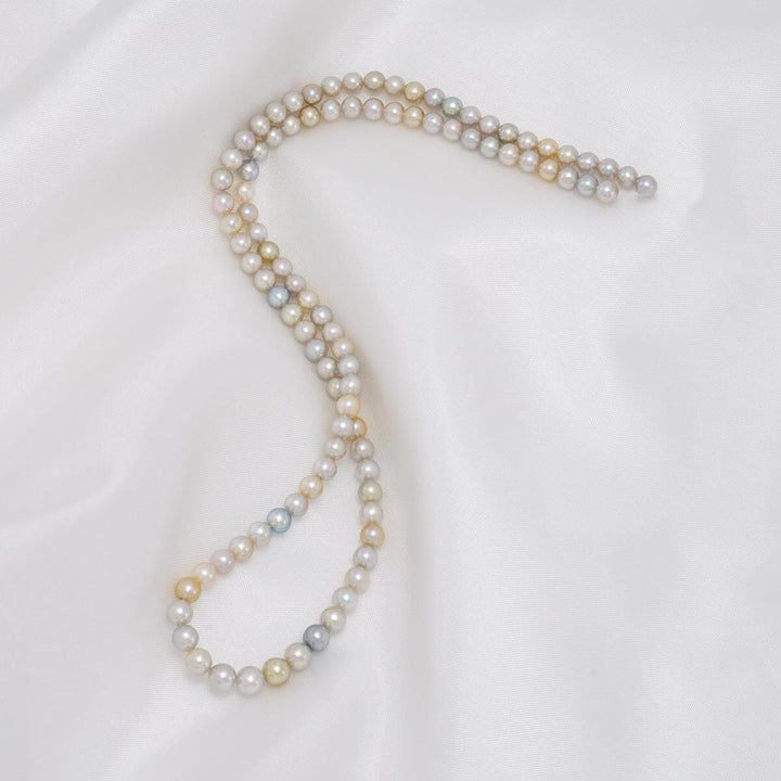 TF-26: 4-5 mm Natural Multicolor Akoya Pearl Round Strands beautifully displaying a delicate array of white, pink, yellow, and silver pearls on a soft white background.
