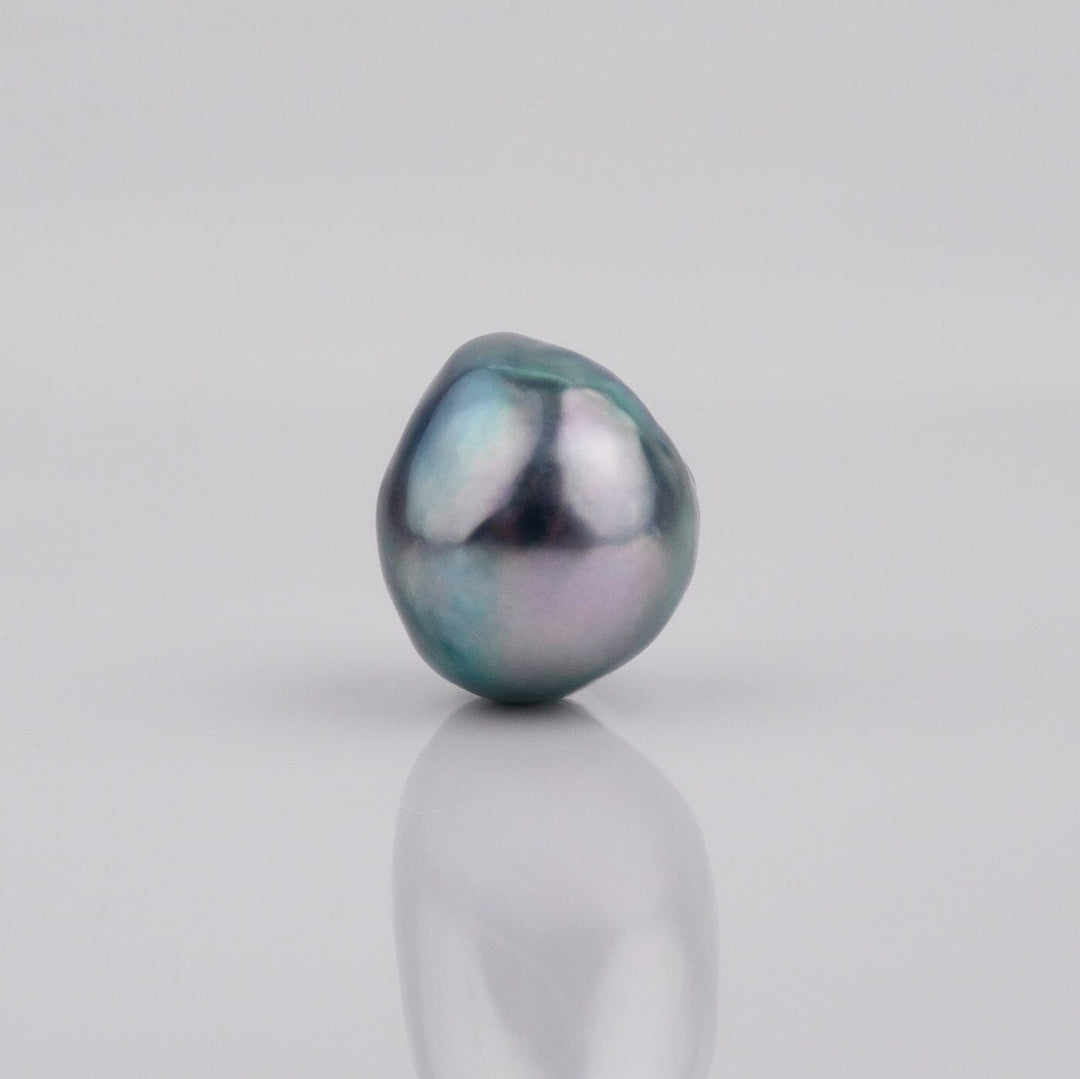 B-11: 10-11 mm Baroque Akoya Pearls featuring an irregular, lustrous dark gray pearl with subtle iridescent hues on a smooth reflective surface.