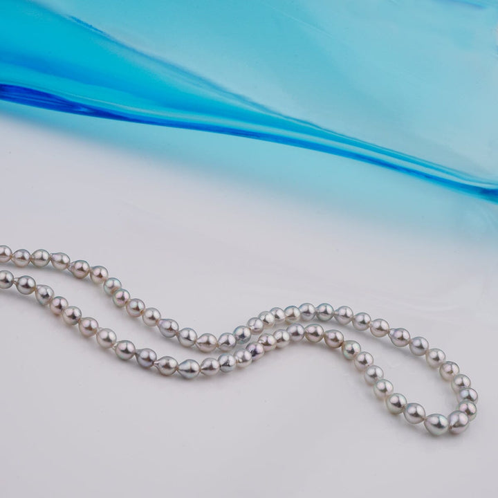 B-12: 3-4.5 mm Silver-blue Drop Akoya Strands, 16-inch Unfinished Strand displayed against a soft blue background, showcasing lustrous cultured pearls.