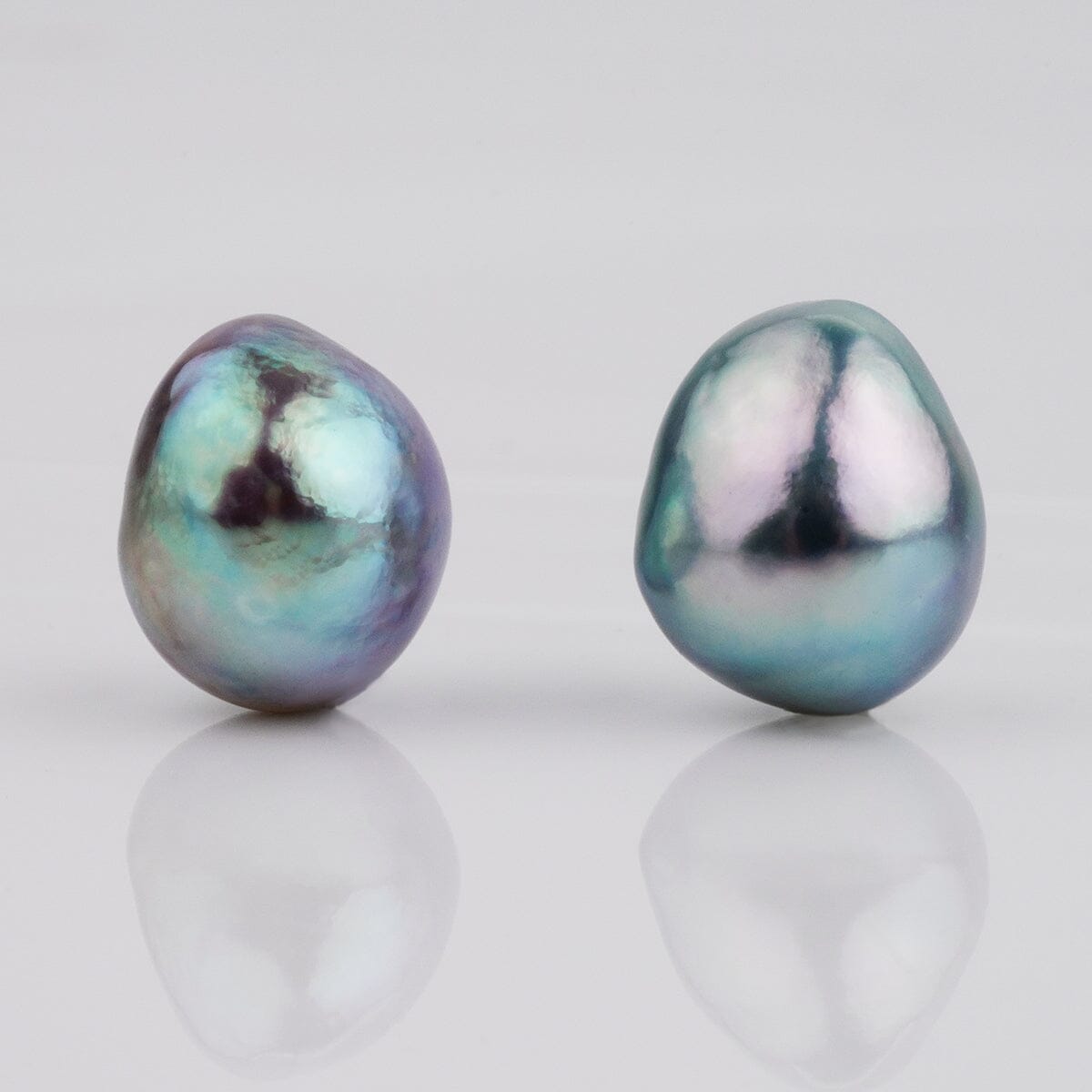 B-9: 9.0-9.5 mm Baroque Blue Akoya Pearl Pairs displaying lustrous, irregular shapes with a unique blue and green iridescent sheen on smooth surfaces.