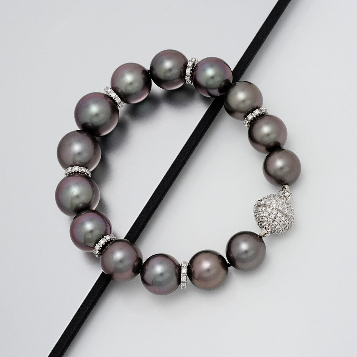 Assael Collection: 10.9–13.1 mm Tahitian Pearl and Diamond Bracelet featuring lustrous dark pearls separated by diamond-encrusted spacers and a sparkling diamond clasp.