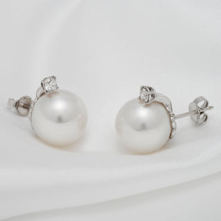 Assael Collection: 13.0 mm White South Sea Pearl and Diamond Earrings featuring lustrous white pearls set with sparkling diamonds on a 18K white gold backing, displayed on a white fabric background.