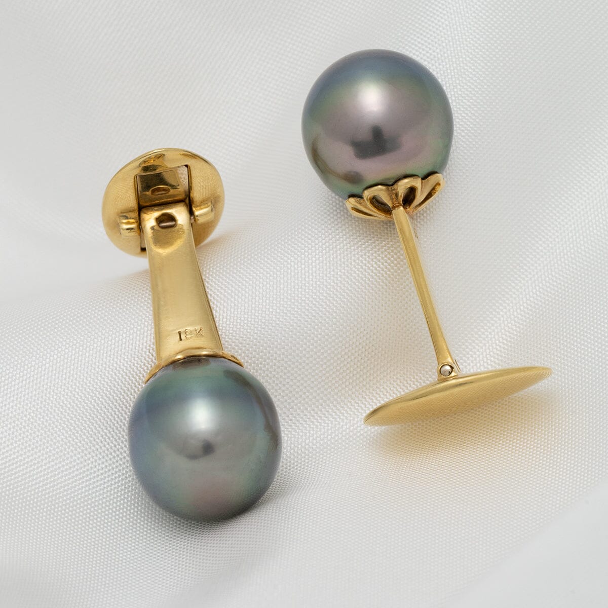 Pair of elegant gold cufflinks featuring lustrous dark Tahitian pearls, showcasing the Assael Collection: 12.0 x 12.4 mm Tahitian Pearl Cufflinks on a soft white fabric background.