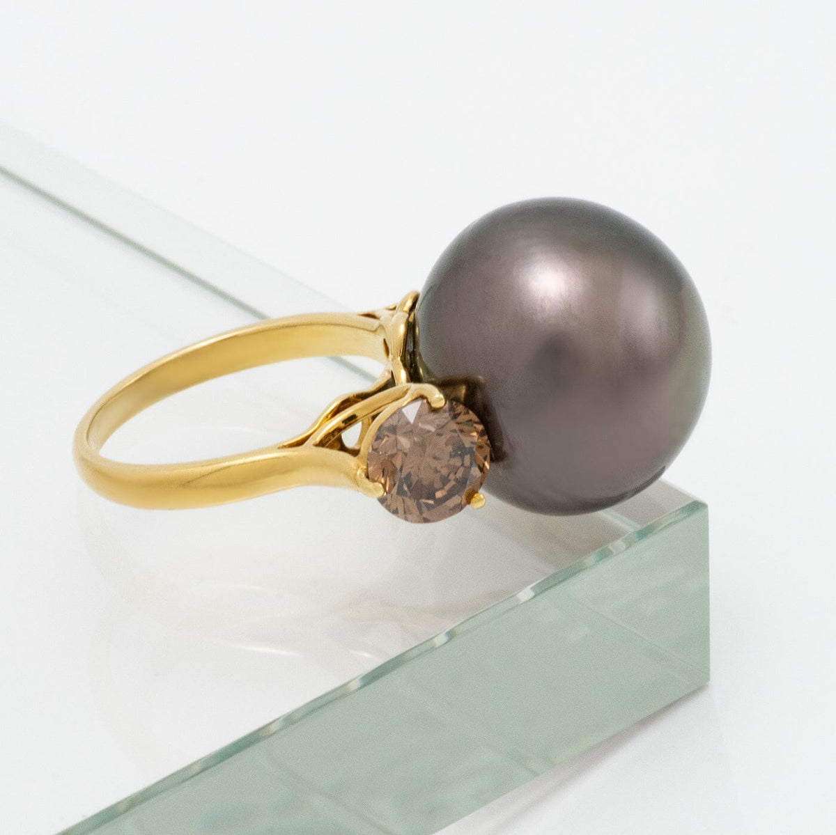 Assael Collection: 16.5 mm Tahitian Pearl and Brown Diamond Ring featuring a large dark Tahitian pearl set beside a sparkling brown diamond on a polished gold band.
