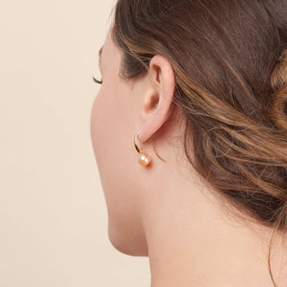Woman wearing a single elegant hoop earring featuring a pink freshwater pearl, showcasing the Cascade Collection 8.5-9.0 mm Pink Freshadama Pearl Earrings style.