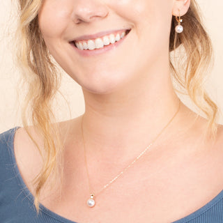 Close-up of a woman wearing the 8.5-9.0 mm White Freshadama Pearl and Diamond Harmony Pendant and Earrings Set featuring delicate white pearls and diamond accents on gold settings.